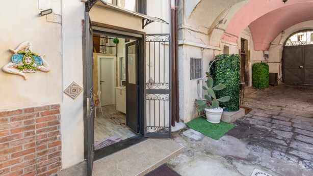 An entrance with a metal gate, a potted plant, and a tiled floor. - Apartment 'Catania Del Mio Cuore' – Central, Sleeps 6, Family-Friendly (Catania)