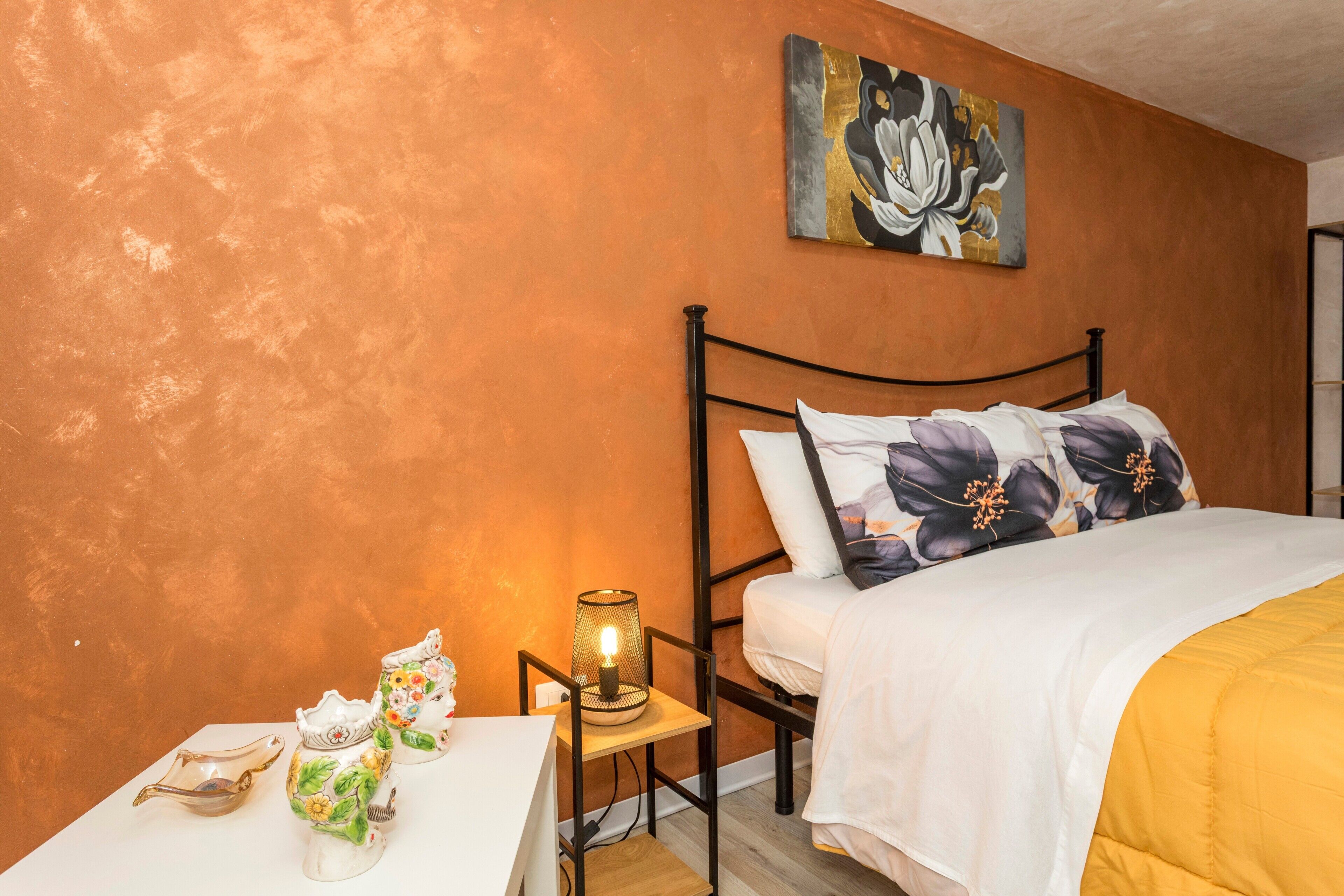 A bedroom with a bed, a nightstand, a lamp, and a painting on the wall.