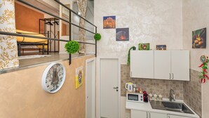 A compact kitchen with a microwave, sink, and cabinets, a small dining area with a bench, and a staircase leading to an upper level. - Apartment 'Catania Del Mio Cuore' – Central, Sleeps 6, Family-Friendly (Catania)