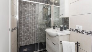 A modern bathroom with a glass-enclosed shower, a white sink, and a mirror above it. - Apartment 'Catania Del Mio Cuore' – Central, Sleeps 6, Family-Friendly (Catania)
