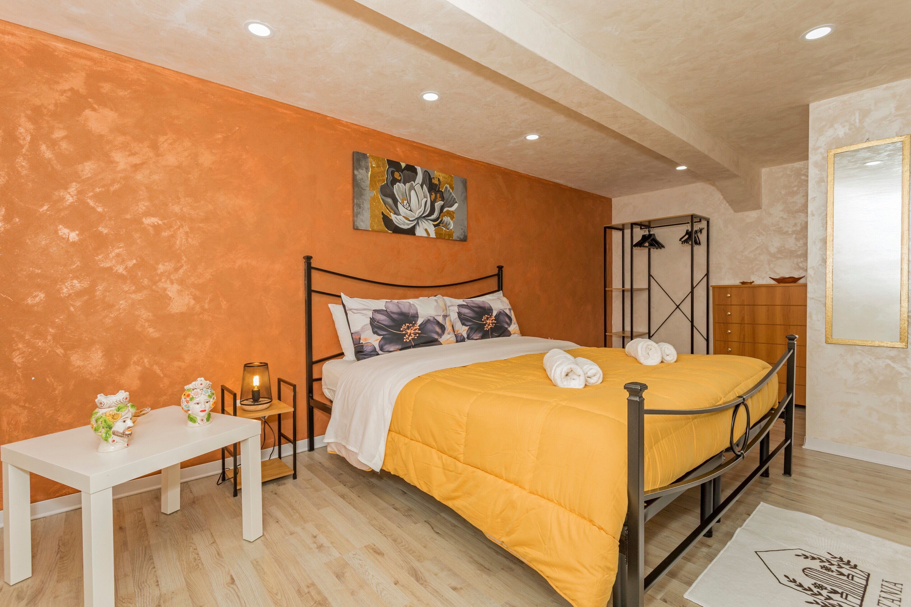 A bedroom with a bed, a bedside table, a lamp, and a painting on the wall.