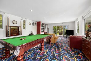 A pool room with a green pool table, a clock, and a billiard rack. - Point View Beach House (Lorne)