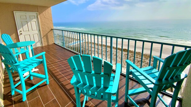 A balcony with turquoise Adirondack chairs, a door, and a view of the beach and ocean. - Gorgeous Beachfront;  Walk to restaurants! (Gulf Shores)