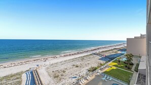 A beach view from a balcony with a clear sky, a sandy beach, and a pool area. - Gorgeous Beachfront;  Walk to restaurants! (Gulf Shores)