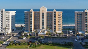 A high-rise hotel with a central atrium, a parking lot, and a beachfront view. - Gorgeous Beachfront;  Walk to restaurants! (Gulf Shores)