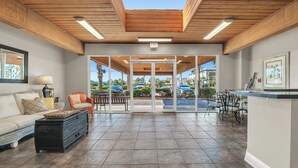 A spacious living area with a wooden ceiling, a sofa, a coffee table, and a glass door leading outside. - Gorgeous Beachfront;  Walk to restaurants! (Gulf Shores)