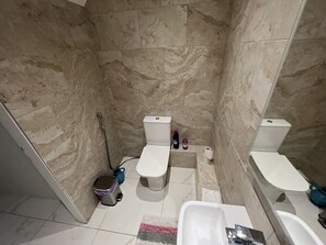 Ein Badezimmer mit zwei Toiletten, einer Dusche, einem Waschbecken und einem Mülleimer.