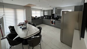 Una cocina moderna con encimera de mármol, sillas negras y refrigerador de acero inoxidable.