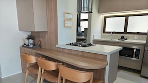 Eine moderne Küche mit einer zentralen Kochinsel, Holzstühlen, einem eingebauten Herd und einer Mikrowelle.