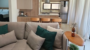 Ein modernes Wohnzimmer mit einer Couch, einem kleinen Tisch und einer Küchenzeile im Hintergrund.