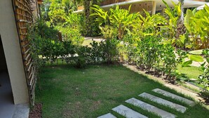 Ein Garten mit einem Betonweg, üppigem Grün und einem Bambuszaun.