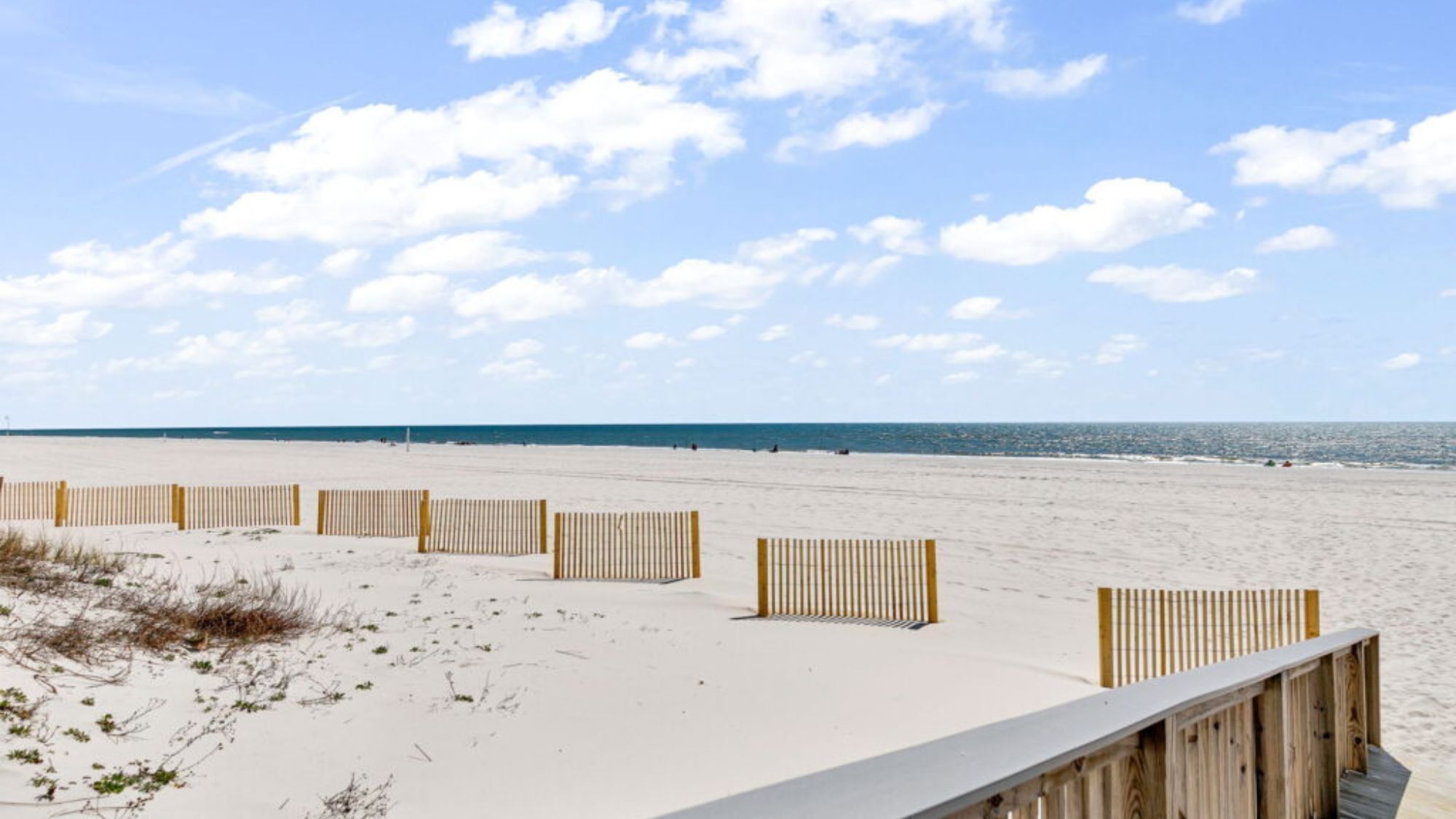 A sandy beach with wooden barriers and a clear sky.