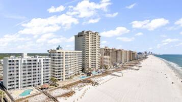 A beachfront hotel with multiple buildings, a sandy beach, and a clear sky.