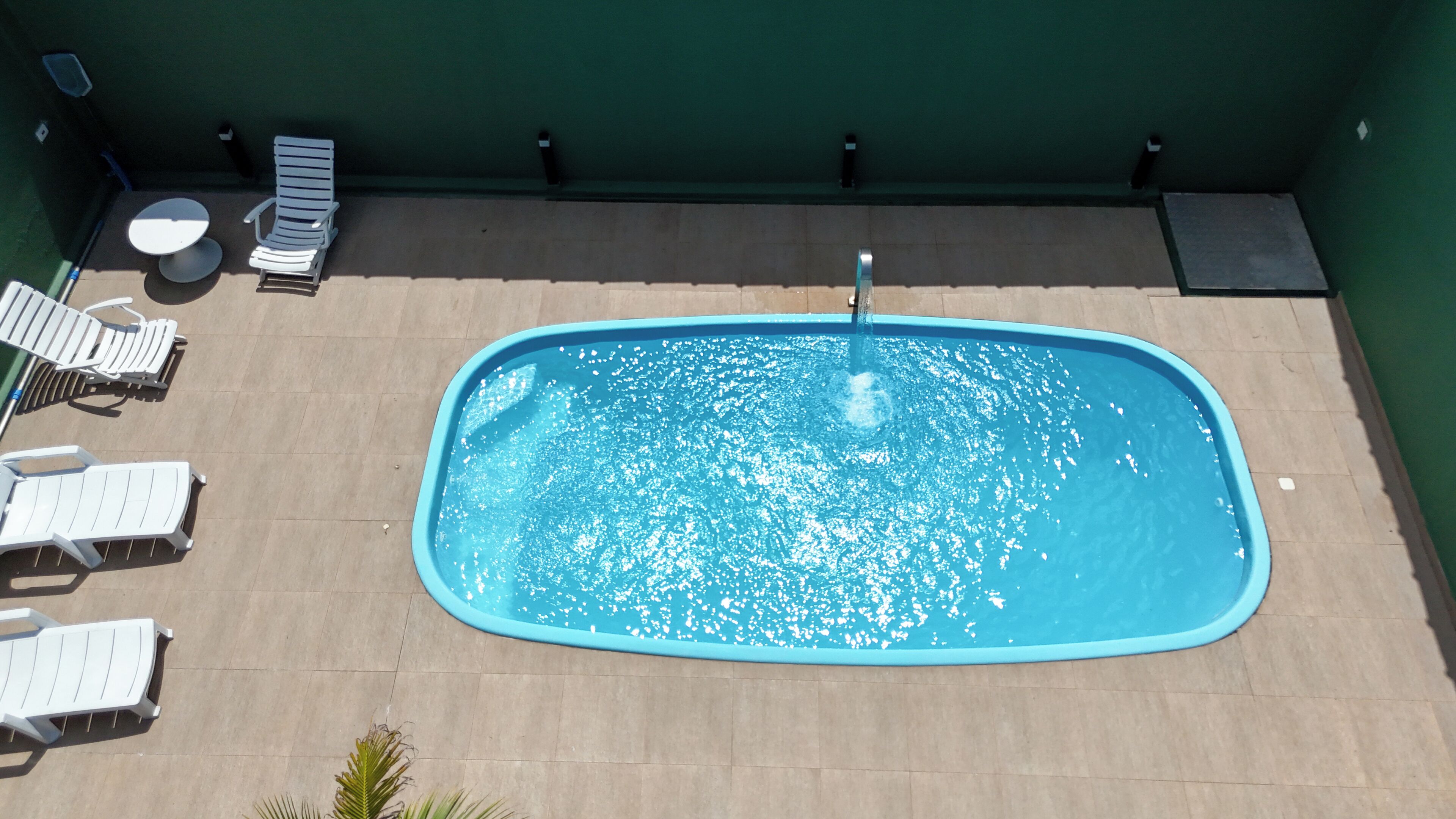 Una piscina en la azotea con sillones de descanso y una pequeña mesa.