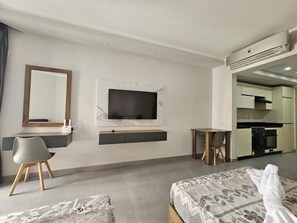 A modern hotel room with a bed, a desk, a chair, a TV, and a kitchenette. - Scandic Resort C310 (Hurghada)