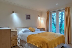A bedroom with a bed, bedside tables, a dresser, and a window with curtains. - 20 Chy Lowen (Newquay)