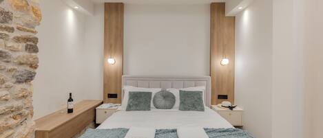 Une chambre moderne avec un mur d’accent en pierre, une tête de lit en bois et un lit avec deux oreillers et une couverture.
