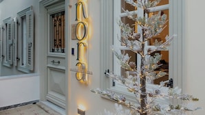 Facciata di un edificio con un abete decorato con decorazioni trasparenti, un cartello al neon e un pavimento a motivi.