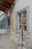Fachada de edificio con un árbol de Navidad iluminado y un letrero de neón, además de un piso con diseño.
