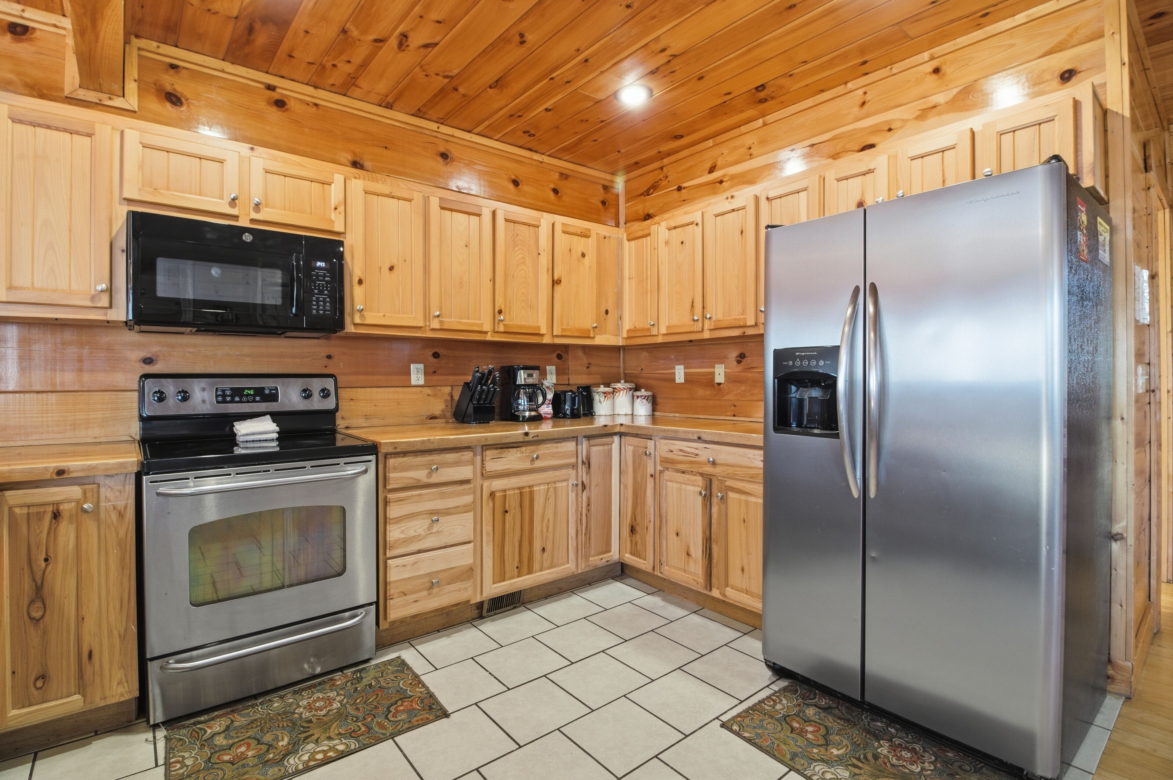 A kitchen with wooden cabinets, a stainless steel refrigerator, a microwave, and an oven.