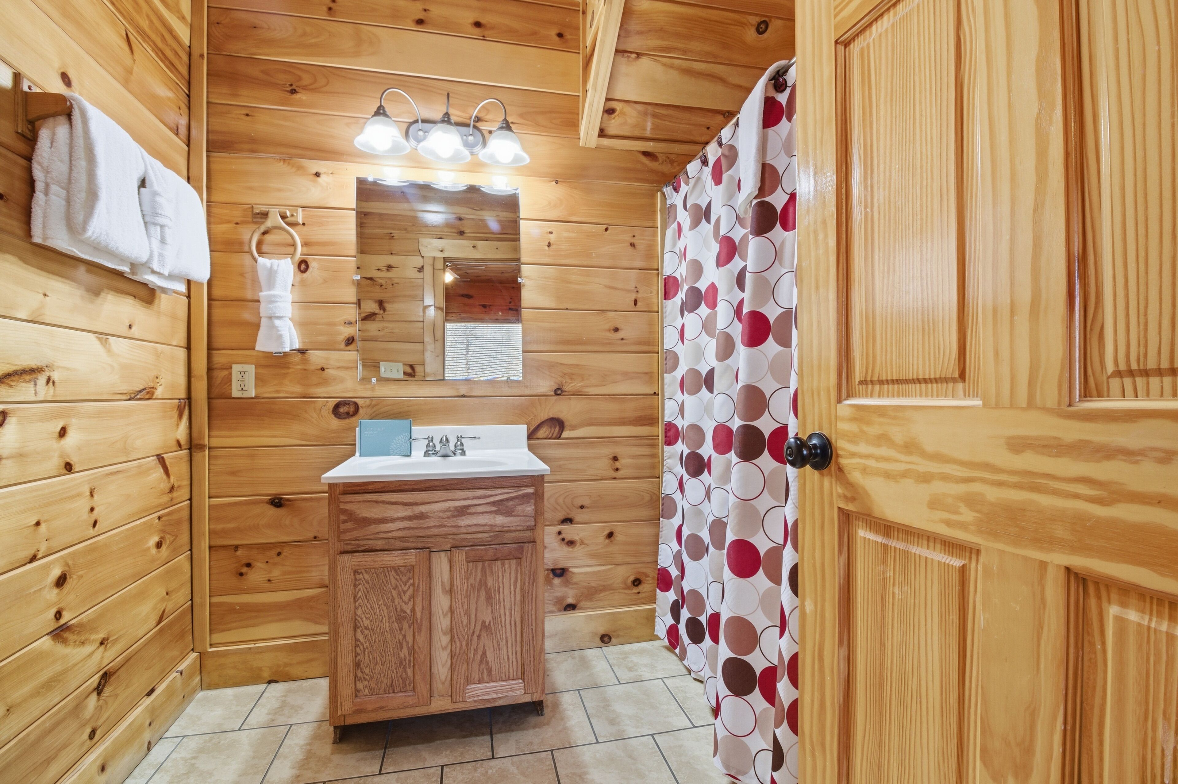 Un baño de madera con lavamanos, espejo y barra para toallas.