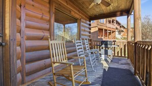 En stuga byggd av trästockar med en veranda med gungstolar och en grill.