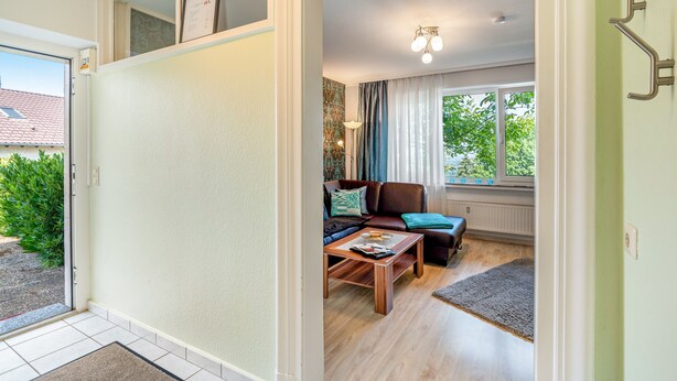 A living room with a sofa, coffee table, and a window with curtains. - Baden-Chalet – Charming Apartment with Views over the Rhine Valley (Bühl)