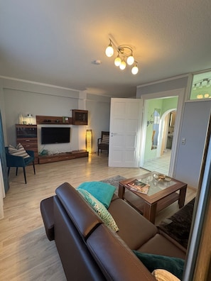 Ein Wohnzimmer mit Sofa, Couchtisch, Fernseher und Lampe.