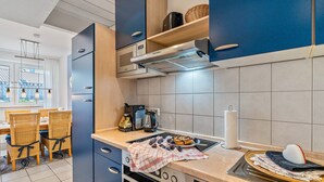 A modern kitchen with a built-in oven, a coffee maker, and a kettle on the countertop. - Baden-Chalet – Charming Apartment with Views over the Rhine Valley (Bühl)