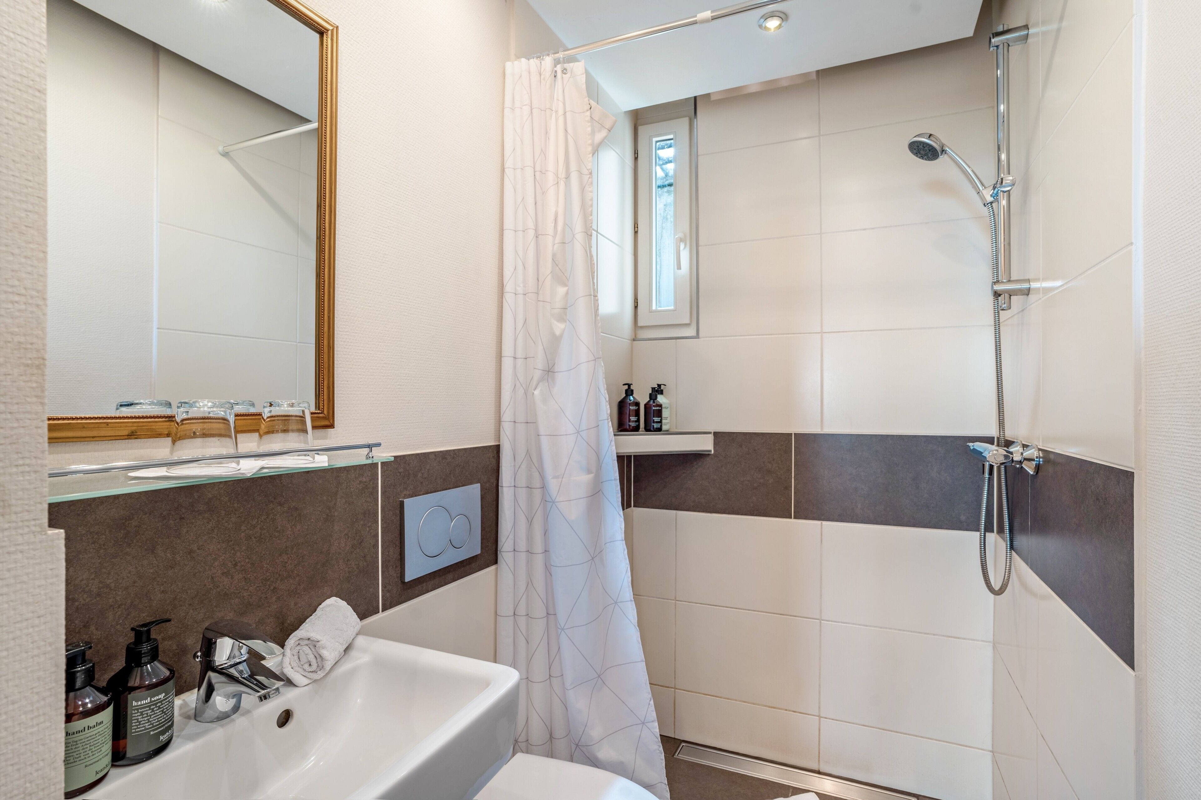 Ein modernes Badezimmer mit Badewanne, Dusche und Waschtisch mit Toilettenartikeln.