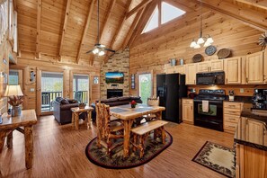 Interior de una cabaña de madera con comedor, cocina y sala de estar.