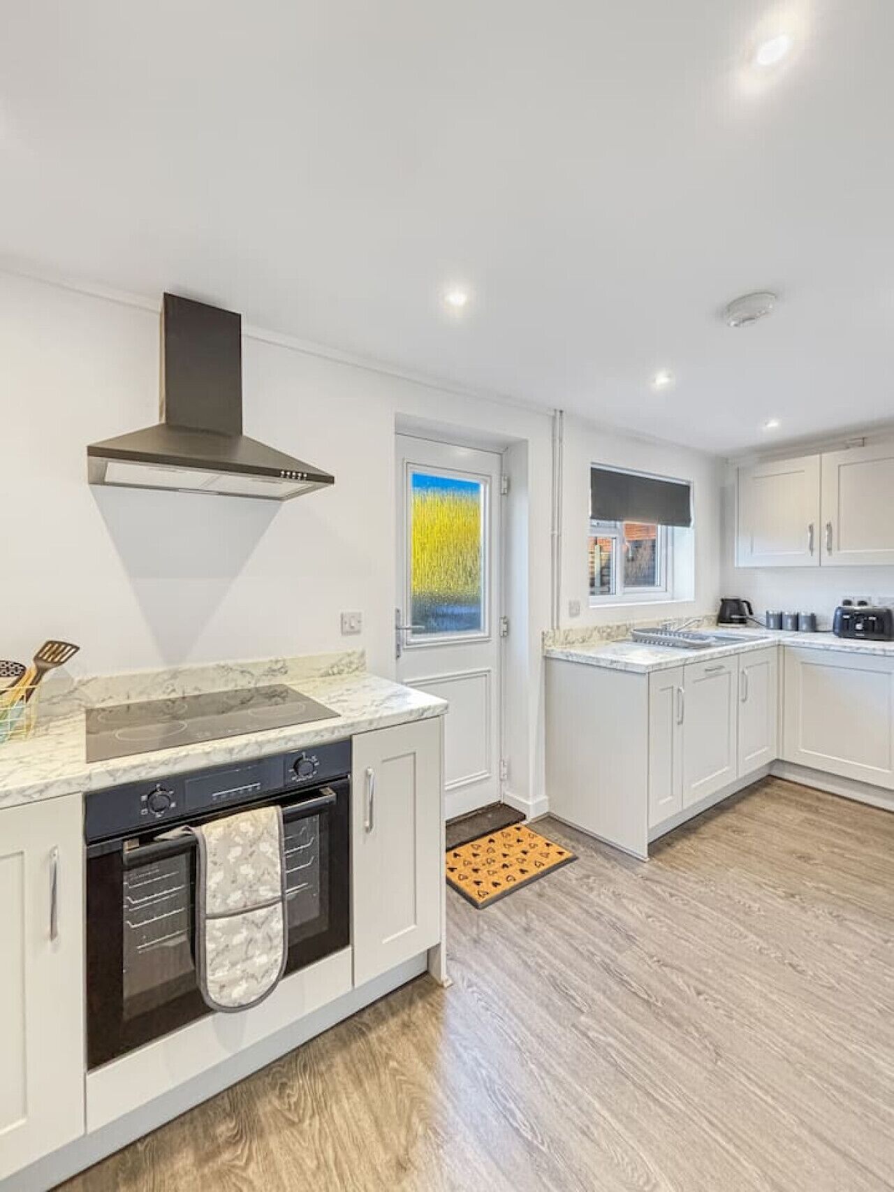 A modern kitchen with white cabinetry, a built-in oven, a stove, and a range hood.
