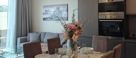 Un comedor moderno con una mesa de vidrio, sillas marrones y un jarrón con flores.