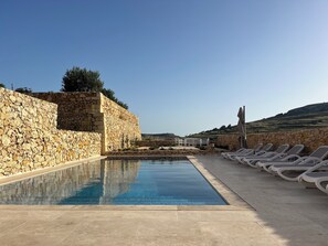 Ein Poolbereich mit Steinmauern und Liegestühlen.
