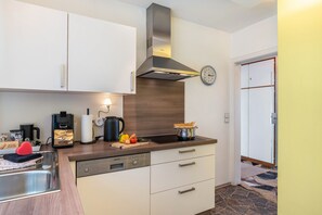 Eine moderne Küche mit Geschirrspüler, Kaffeemaschine, Wasserkocher und einer Portion Spaghetti.