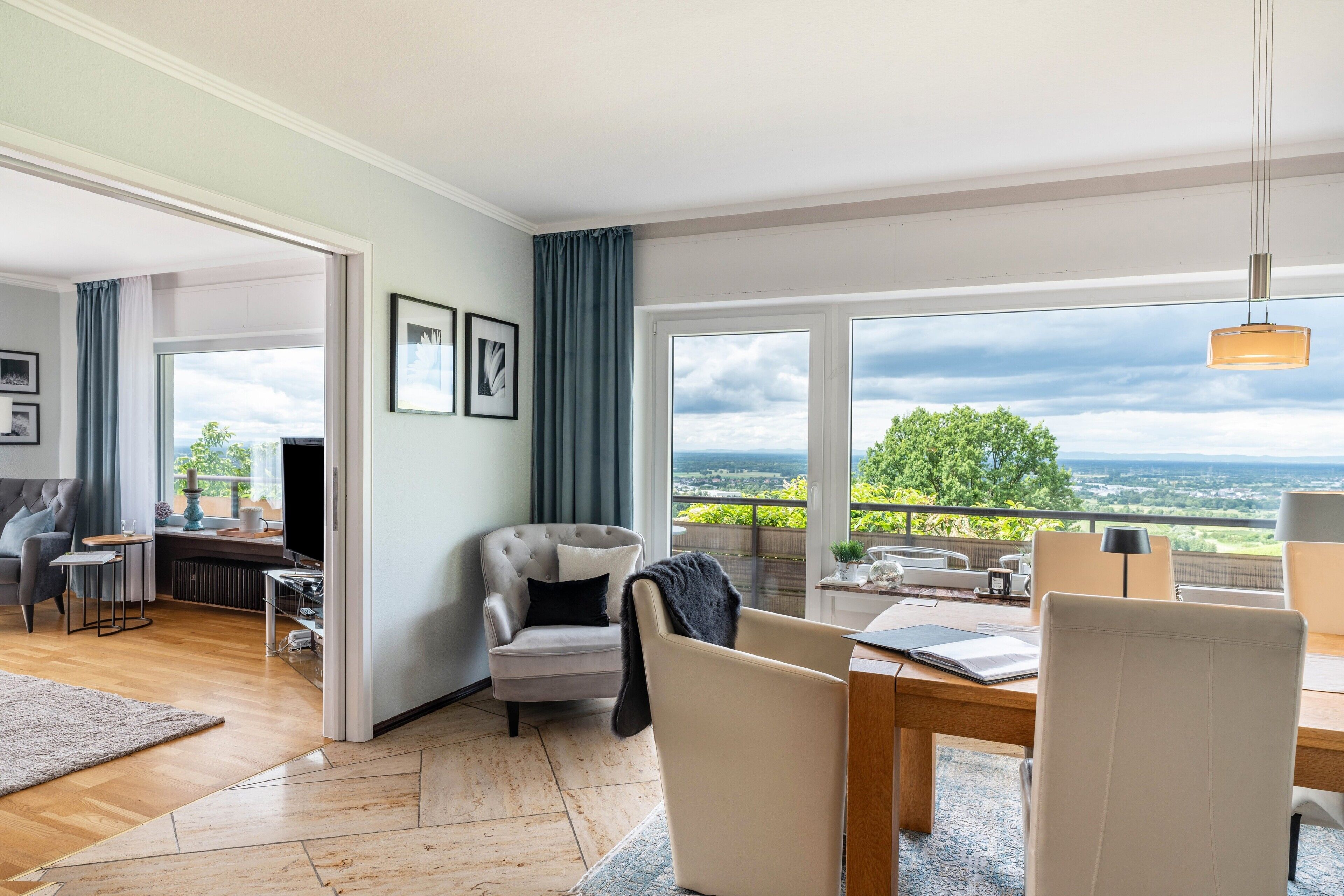 Ein modernes Wohnzimmer mit großem Fenster, Essbereich und Blick auf die Landschaft.