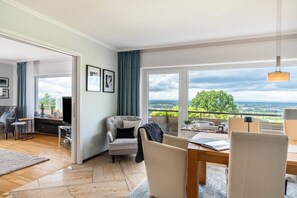 A modern living room with a large window, a dining area, and a view of the landscape. - Apartment House - Baden Chalet - Panoramic Rhine Valley Views near Baden-Baden & Black Forest (Bühl)