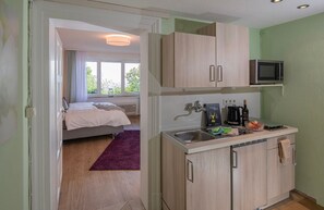 Ein kleines Zimmer mit Bett, einer Küchenzeile und einem Fenster.