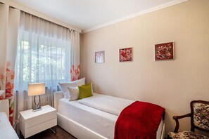 Habitación de hotel con cama, mesita de noche con lámpara, una silla y tres obras de arte colgadas en la pared.