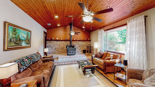 Ein gemütliches Wohnzimmer mit Kamin, einer Couch, einem Couchtisch und einem Deckenventilator.