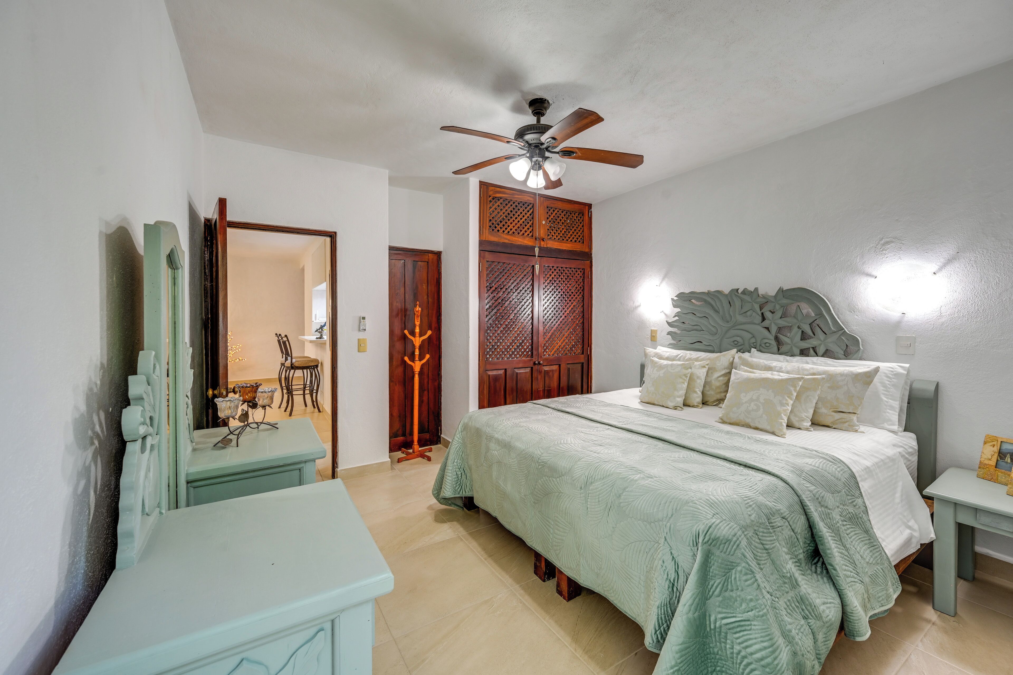 A bedroom with a bed, a ceiling fan, a nightstand, and a dresser.