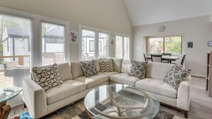 A living room with a sectional sofa, a glass coffee table, and a dining area with a table and chairs. - 1 Mi to Rice! Pet-friendly, Modern Apt in Houston (Houston)