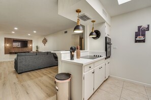 A modern kitchen with a central island, white cabinetry, and a built-in oven. - Summer-ready Old Town Condo w/ Pool & Patio Access (Scottsdale)
