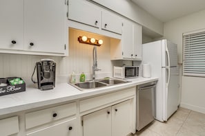 A modern kitchen with white cabinets, a coffee machine, a microwave, a refrigerator, and a built-in sink. - Summer-ready Old Town Condo w/ Pool & Patio Access (Scottsdale)