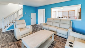 A living room with a staircase, beige sofas, a coffee table, and a large window with blinds. - Hot Tub & Sauna! Atlantic City Getaway By Beach (Atlantic City)