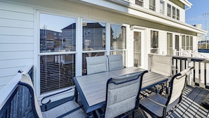 A covered outdoor seating area with a table and chairs, large windows, and a white railing. - Hot Tub & Sauna! Atlantic City Getaway By Beach (Atlantic City)