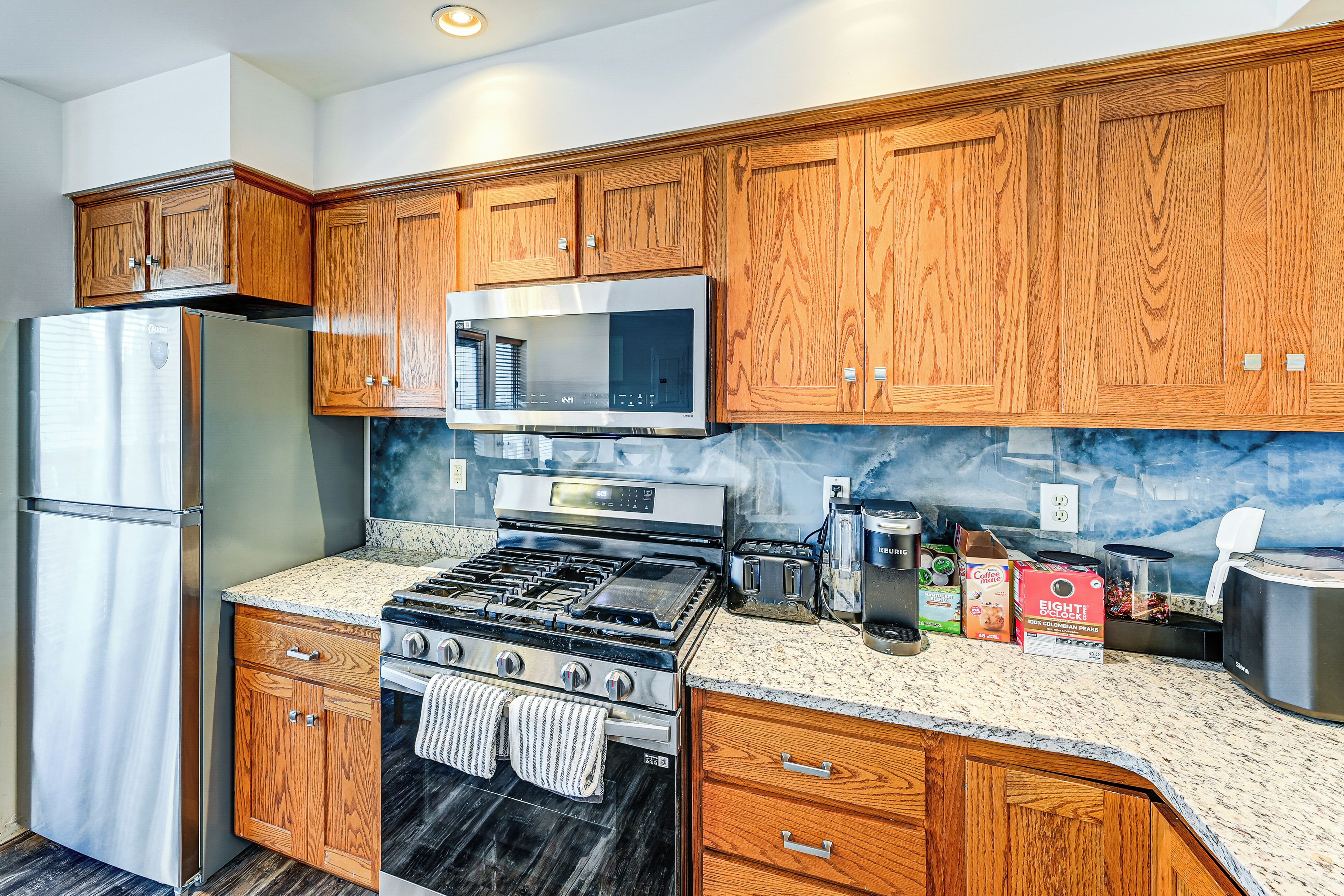 A kitchen with wooden cabinets, stainless steel appliances, a granite countertop, and a built-in microwave.