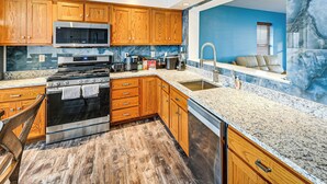 A kitchen with wooden cabinets, a stainless steel stove, a microwave, and granite countertops. - Hot Tub & Sauna! Atlantic City Getaway By Beach (Atlantic City)
