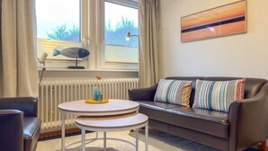 A living room with a sofa, a round table, and a radiator. - Vacation apartment Eldorado Laacht (Norddorf)