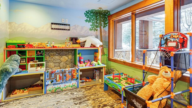 A children's playroom with a toy workshop, a large teddy bear, and a window with a view of trees. - Walk to Gondola! Keystone Gem in River Run Village (Keystone)